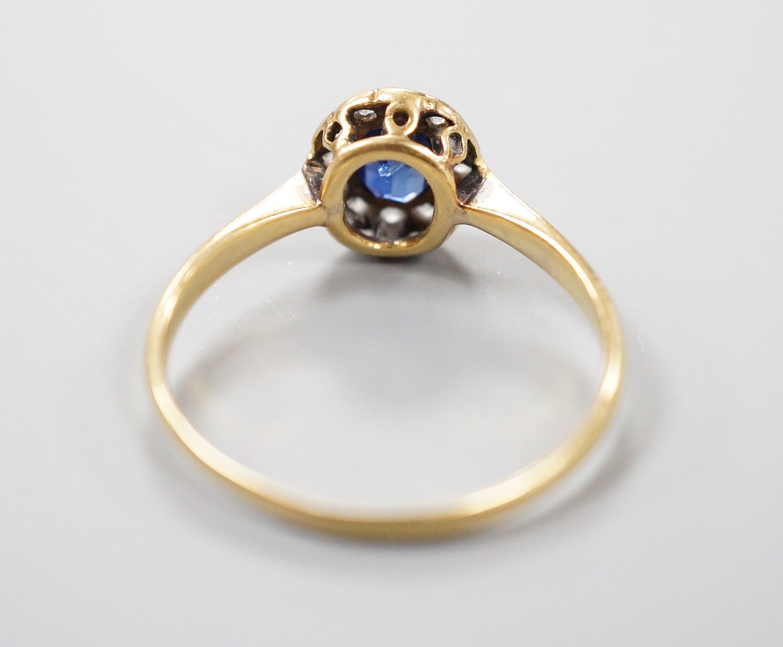 An 18ct, sapphire and diamond set oval cluster ring, size M, gross weight 1.7 grams.